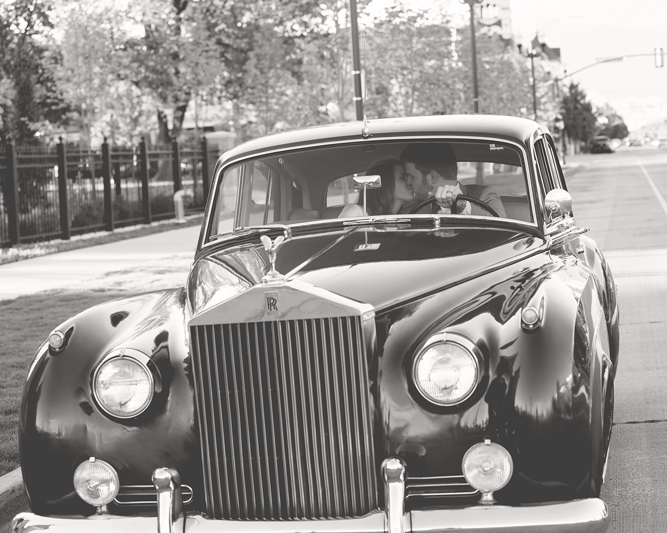 Bride and Groom kissing in Rolls Royce black and white